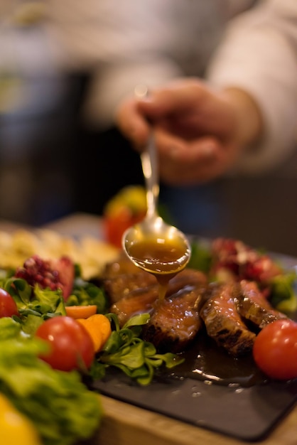 Chef finishing steak meat plate with Finally dish dressing and almost ready to serve at the table