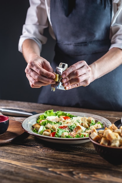 Chef grating the cheese into an appetizing fresh salad