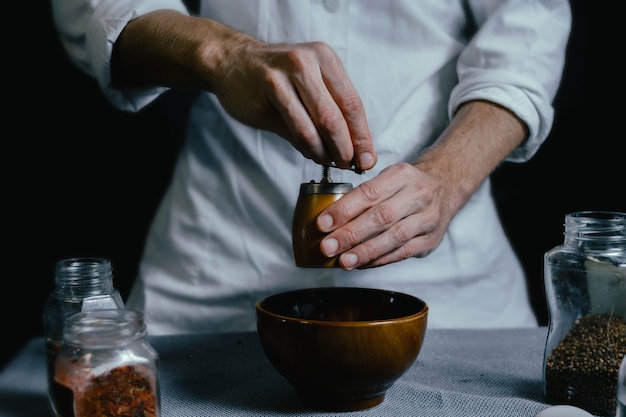 Foto lo chef macina le spezie in un mulino a mano