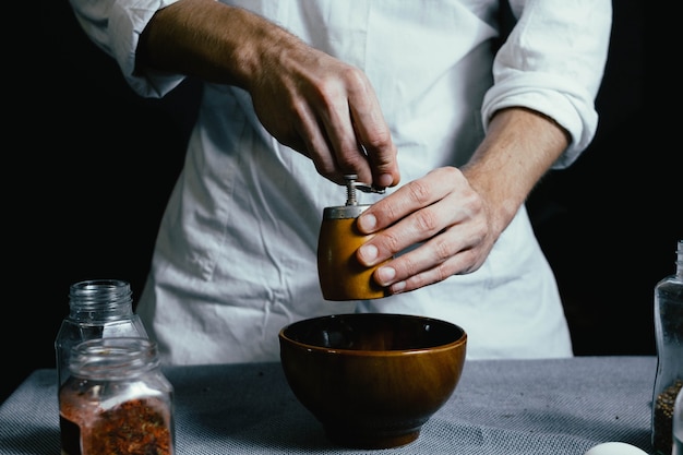 chef grinds the spices in a hand mill