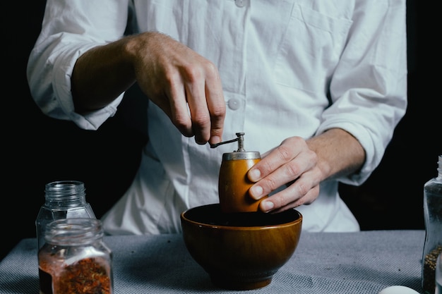 Lo chef macina le spezie in un mulino a mano