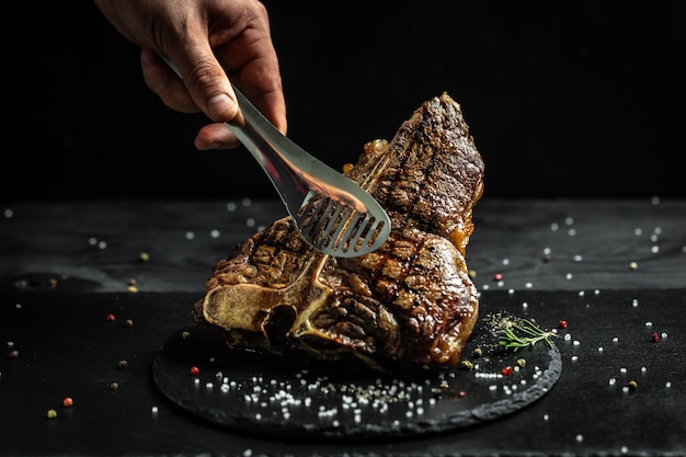 Chef hand with steak meat tongs