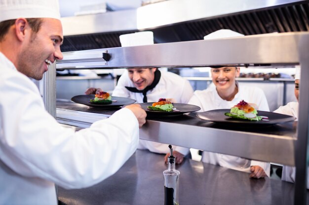 Chef handing appetizer plate through order station