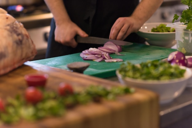 Mani dello chef che tagliano la cipolla con il coltello. preparazione per la cottura. alimentazione sana e stile di vita.