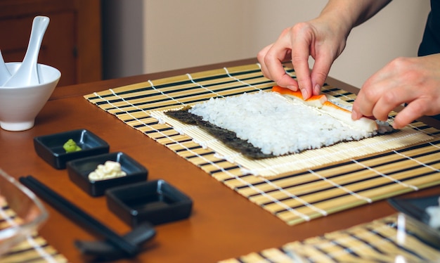 Chef hands placing ingredients on rice to make sushi