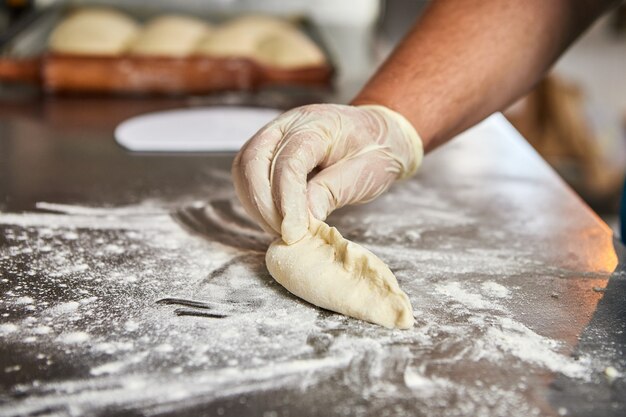 Chef hands prepares apple pies in the restaurant kitchen. The process of making sweet buns. Raw dough for baking in the oven.