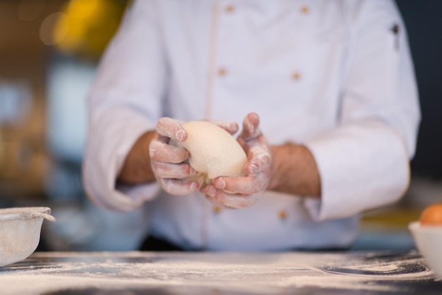 Chef hands preparing dough for pizza on sprinkled with flour\
table closeup