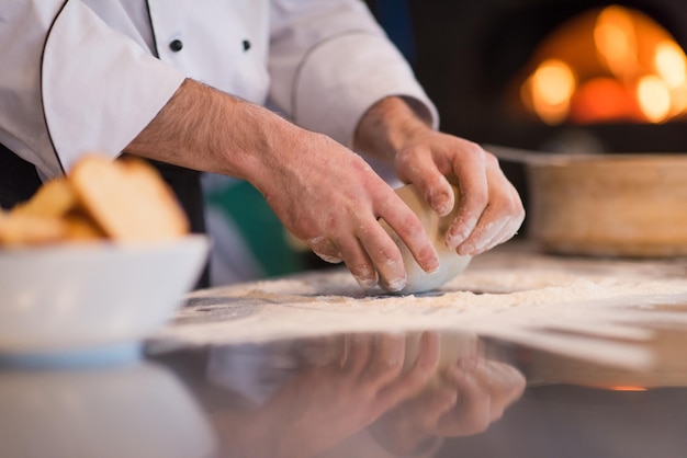 chef hands preparing dough for pizza on sprinkled with flour table closeup