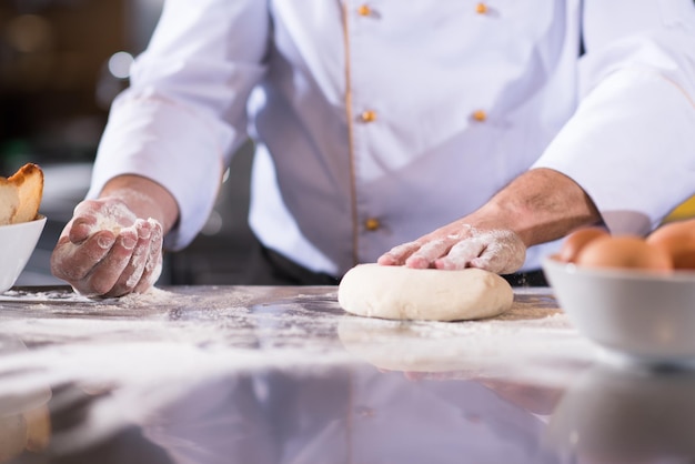 chef hands preparing dough for pizza on table sprinkled with flour closeup