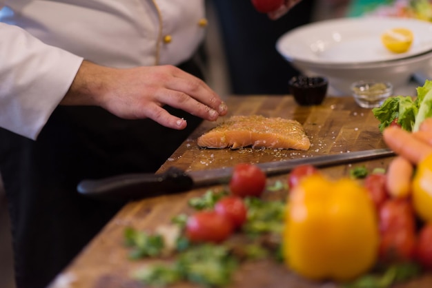 Lo chef prepara il filetto di salmone marinato per la frittura in una cucina del ristorante