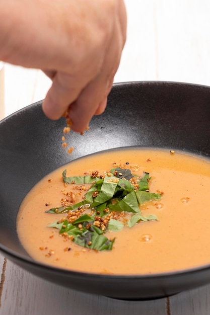 Руки шеф-повара кладут свежий арахис в томатный суп