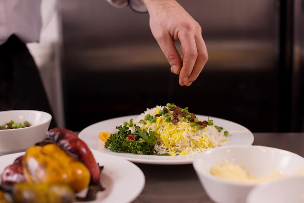 Chef hands serving vegetable risotto on restaurant kitchen