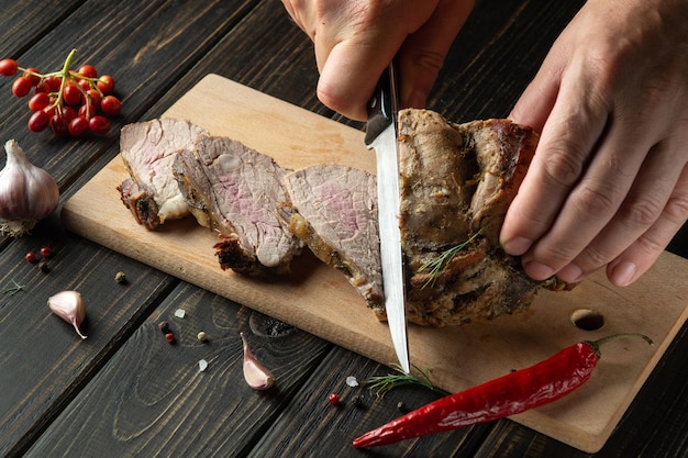 シェフの手が木製のまな板にナイフでビーフ ステーキをスライスします。平面図食品の準備プロセス