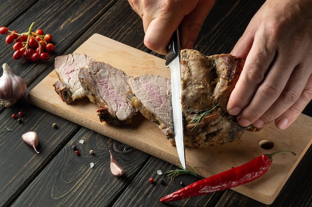 Chef hands slicing beef steak with knife on wood cutting desk Top view food preparation process