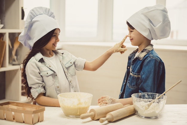 Chef hats are smiling while baking in the kitchen.