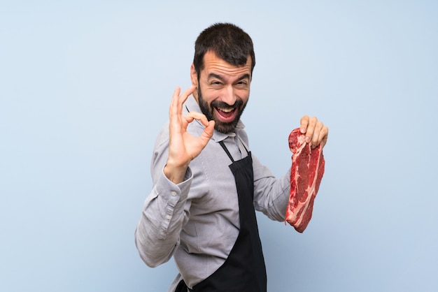 Фото Шеф-повар держит сырое мясо, показывая знак ок и большой палец вверх жест
