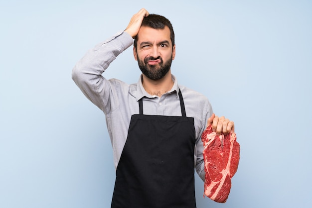 Фото Шеф-повар держит сырое мясо с выражением разочарования и непонимания