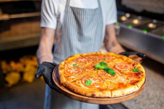 a chef holding a big pizza in his hands