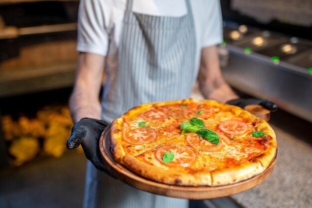 A chef holding a big pizza in his hands