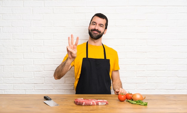 Chef holding in a cuisine happy and counting three with fingers