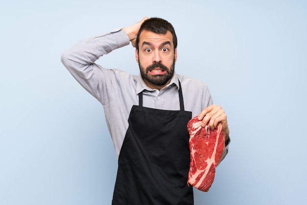 Photo chef holding a raw meat frustrated and takes hands on head