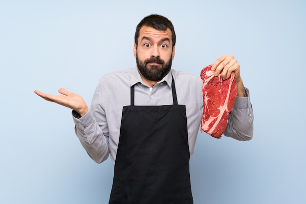 Chef holding a raw meat having doubts while raising hands