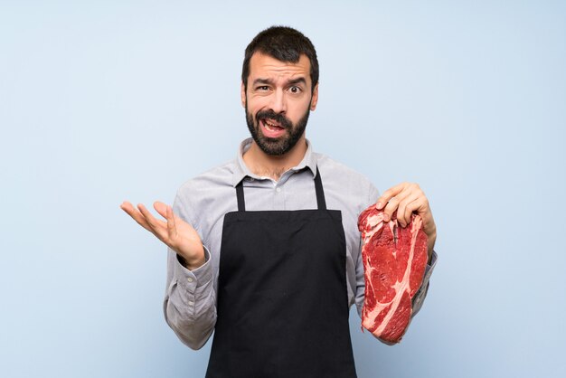 疑わしいジェスチャーを作る生肉を保持しているシェフ