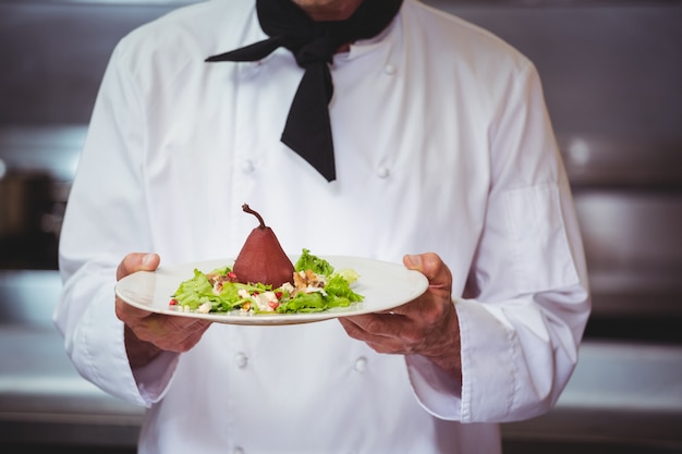 Chef holding and showing a dish with salad