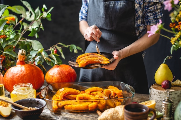 Chef holding slices of baked orange pumpkin with honey and cinnamon