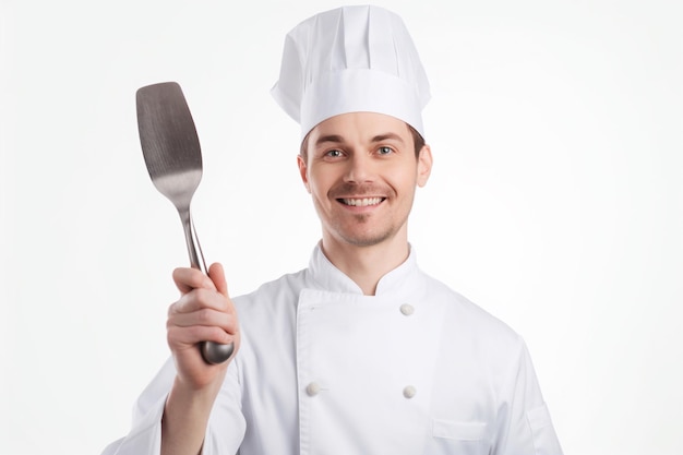 A chef holding a spatula and smiling