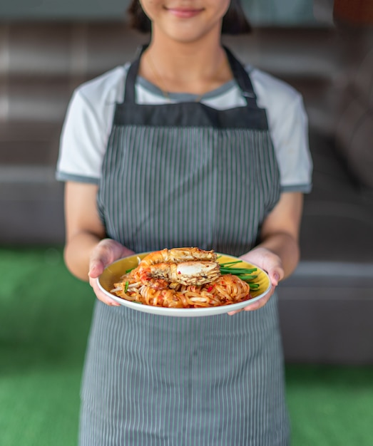 Chef holding stir-fried noodles with prawns