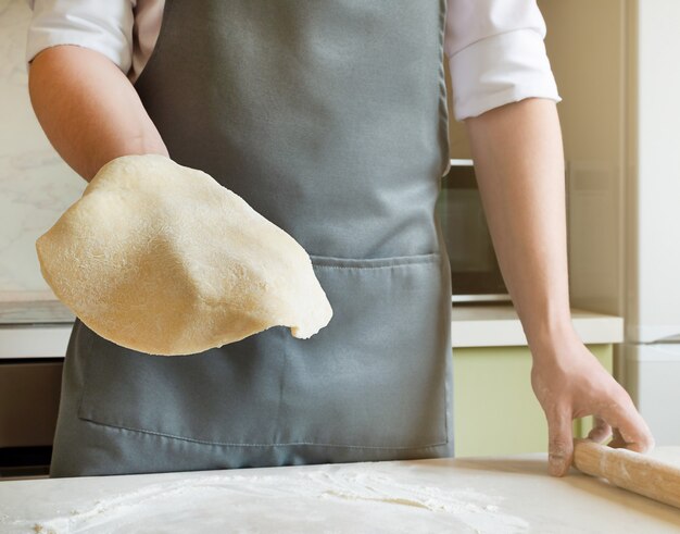 Chef holds a rolled round dough in his hand