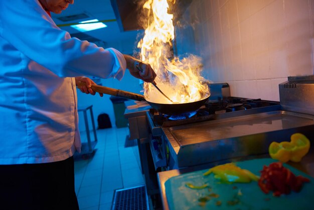 호텔 주방의 요리사는 불로 야채 음식을 준비합니다