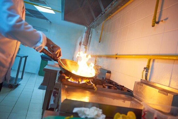 chef in hotel kitchen prepare vegetable  food with fire