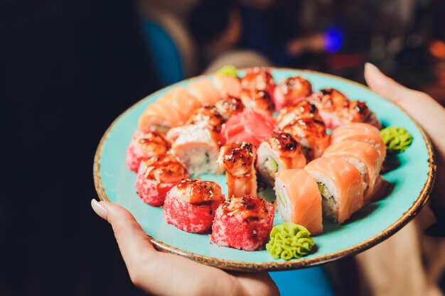 Шеф-повар на кухне отеля или ресторана украшает вкусные роллы с японским майонезом в бутылке. Готовим суши. Только руки.