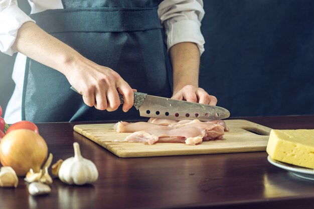 黒いエプロンカットチキンフィレのシェフ