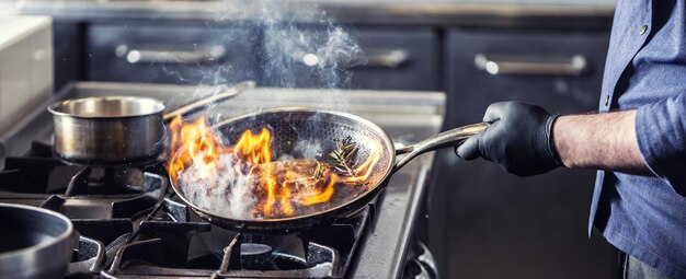 사진 부의 요리사는 을 으로 기울여 술을 마시고 가스 스토브에 불을 붙이기 위해 음식을 불태우기 시작합니다.