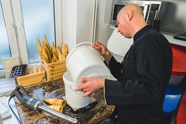 Chef in zwart uniform die ijs maakt professioneel proces van het produceren van heerlijke ijs kaal