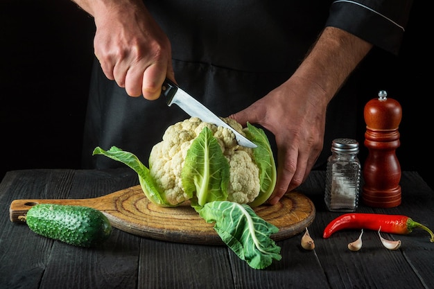 The chef is cutting cauliflower in a restaurant kitchen