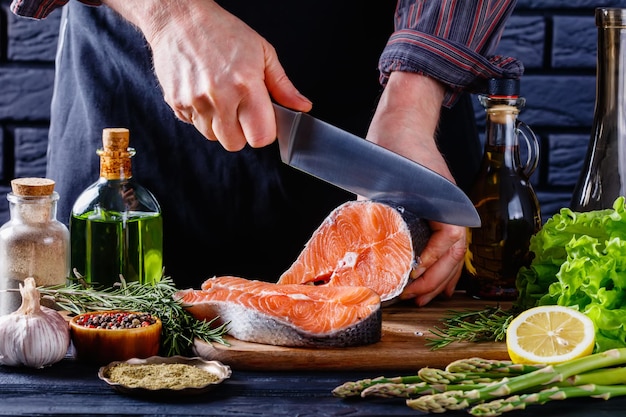 Foto lo chef sta tagliando a fette un pezzo di salmone crudo