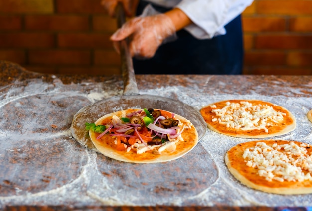 Lo chef sta per mettere la pizza in forno.