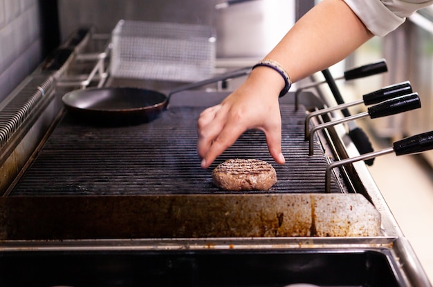 Chef is grilling a meat burger on the grill. Fast cuisine