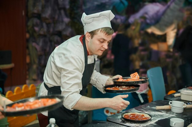 Chef is holding a freshly prepared pizza