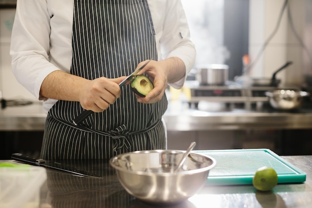 The chef is preparing food Closeup of a male chef peeling an avocado