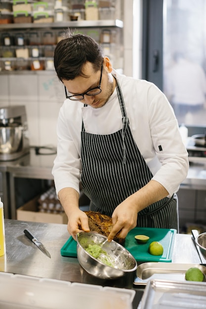 The chef is preparing food Closeup of a male chef preparing avocado toast in a spacious modern kitchen