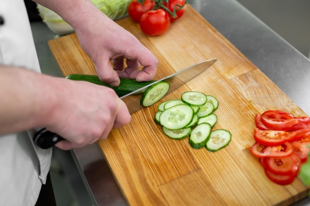 Chef in the kitchen cuts fresh and delicious vegetables for a vegetable salad