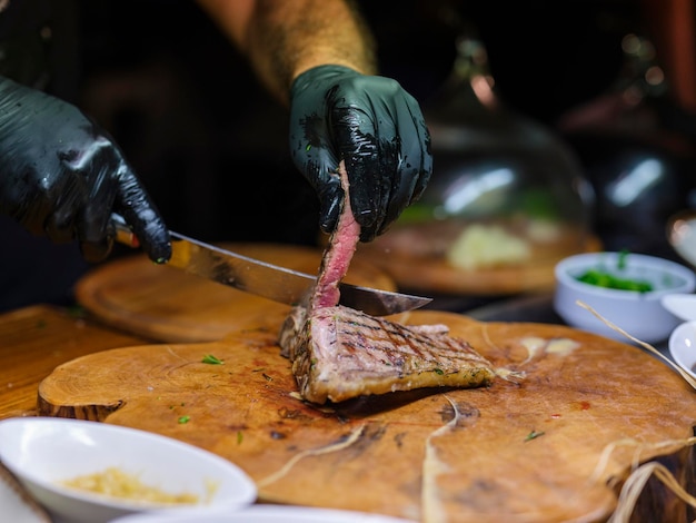 A chef in the kitchen cutting a steak