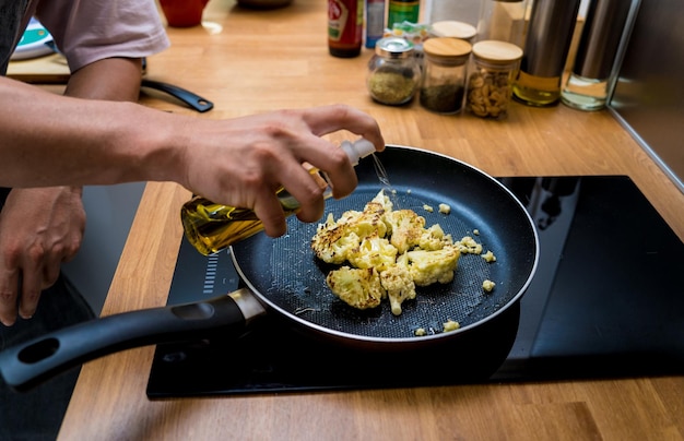 Шеф-повар на кухне готовит бобовую кашу с цветной капустой и овощами