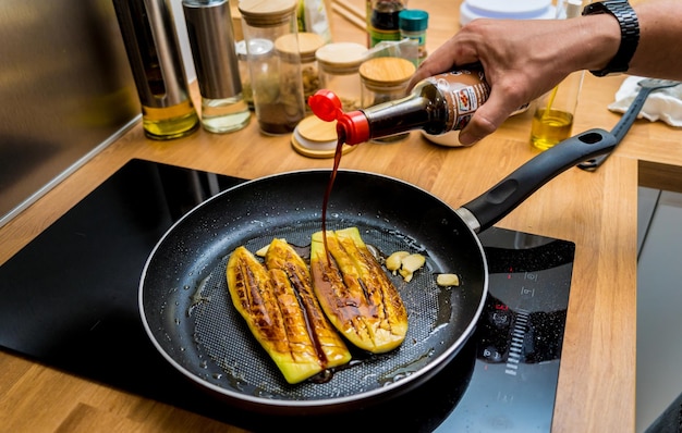 キッチンのシェフがニンニクで焼いた茄子を準備している