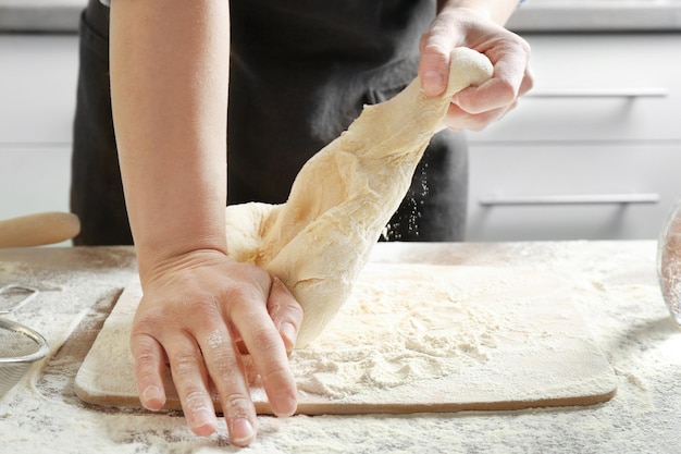 Chef kneading dough in kitchen closeup